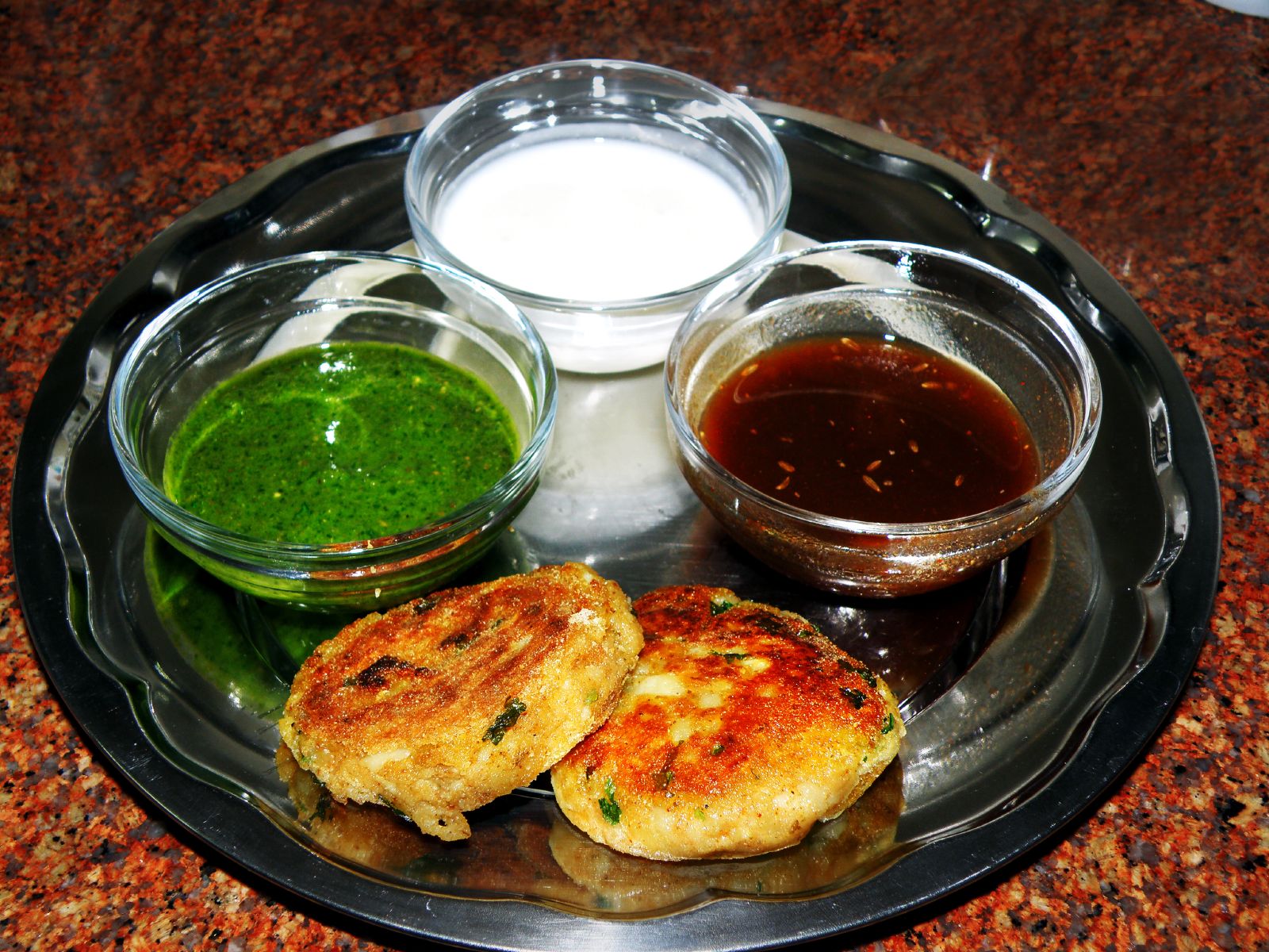 Aloo tikki with green chutney, tamarind chutney and curd