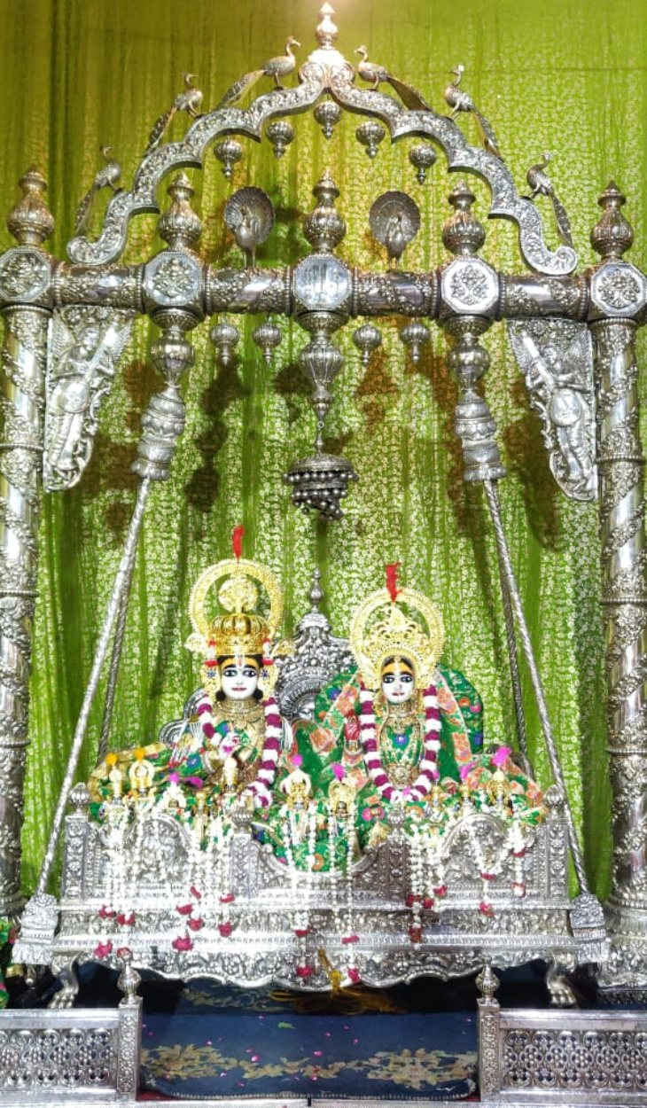 Sawan Jhula Mela — a decorated swing hung in a temple hall, flowers along its ropes
