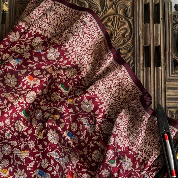 A handloom in a Varanasi weaving workshop, gold zari thread on the warp, the weaver's hands at the shuttle